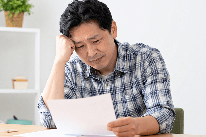 借金に悩み書類を見つめる男性